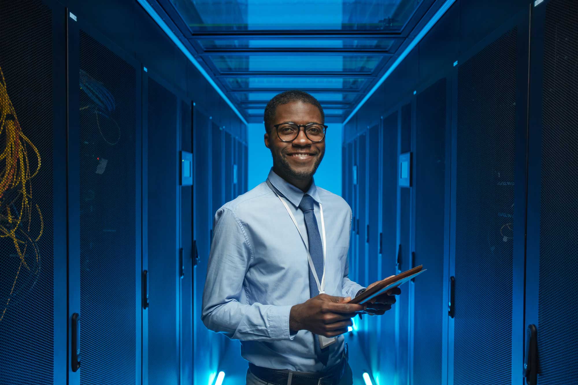 a man standing in a server room holding a tablet